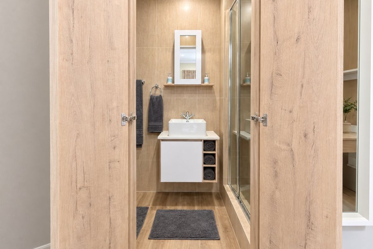 A modern, well-maintained bathroom featuring a wall-mounted vanity with a vessel sink, tiled finishes, and a glass-enclosed shower.