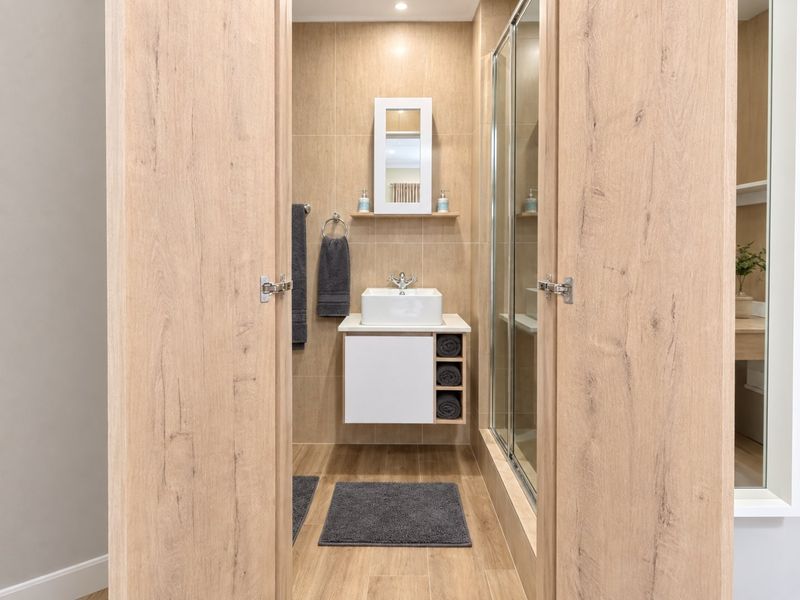 A modern, well-maintained bathroom featuring a wall-mounted vanity with a vessel sink, tiled finishes, and a glass-enclosed shower.