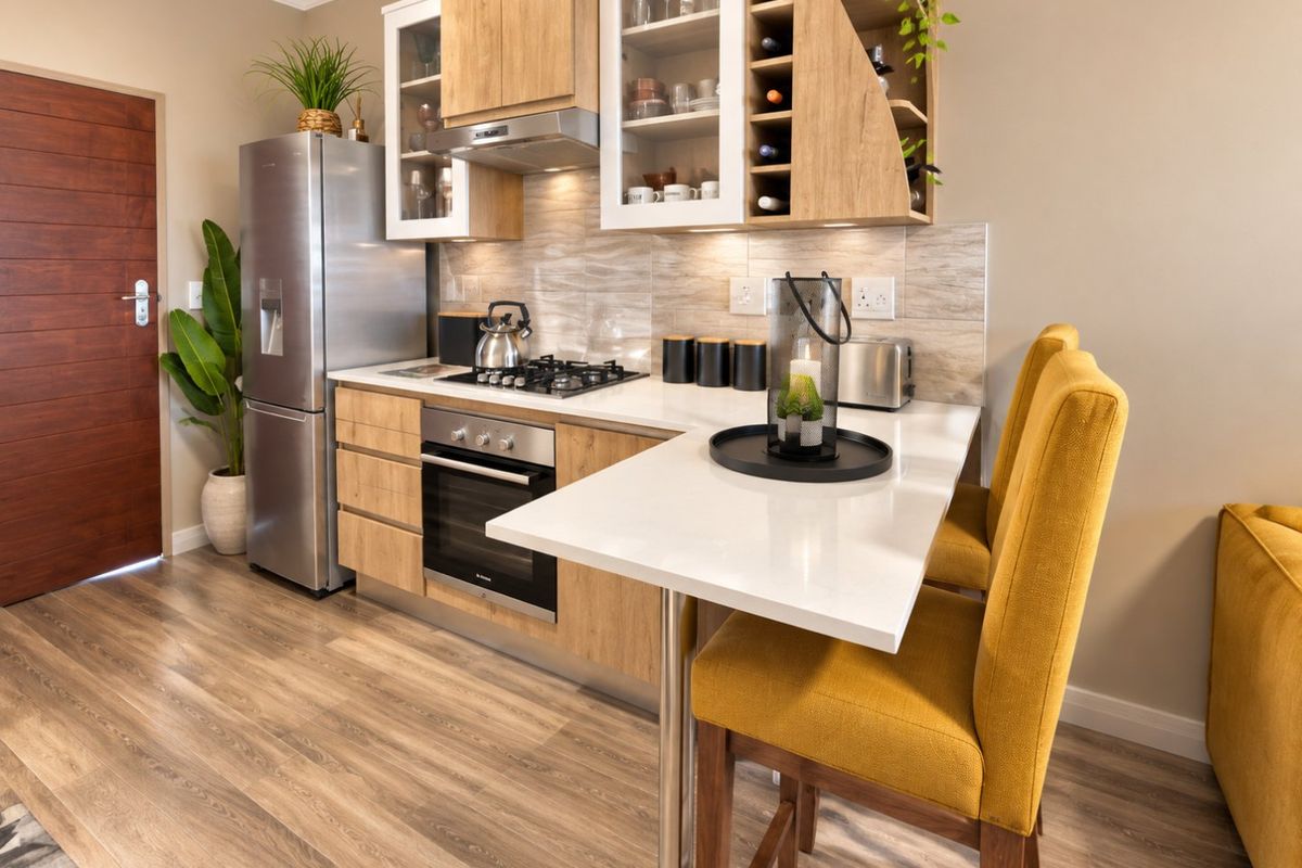 Modern kitchen featuring light wood cabinetry, stone countertops, integrated gas hob, oven, and a breakfast bar with stylish finishes.