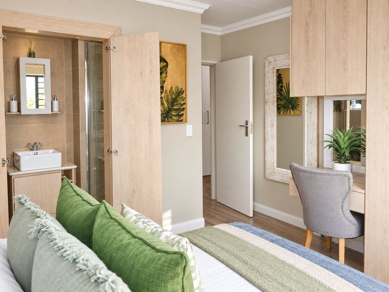 A well-maintained bedroom featuring an en-suite bathroom with a shower, built-in vanity cabinetry, and modern laminate flooring.