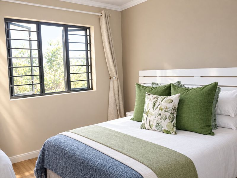 A well-maintained bedroom featuring laminate flooring, neutral wall tones, and a window fitted with security bars.
