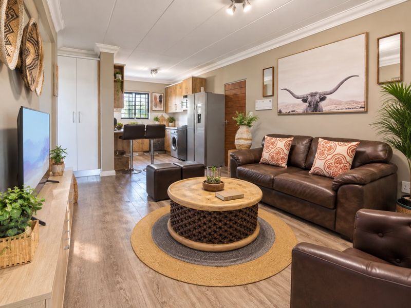 An open-plan living and kitchen area featuring laminate flooring, modern cabinetry, and a breakfast bar, creating a cohesive and functional living space.
