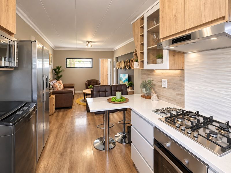 Modern open-plan kitchen and living area featuring sleek cabinetry, quartz countertops, integrated appliances, and durable laminate flooring throughout.