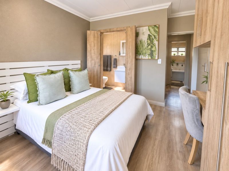 A well-maintained bedroom featuring laminate flooring, built-in cabinetry, and an en-suite bathroom with a modern wall-mounted vanity.