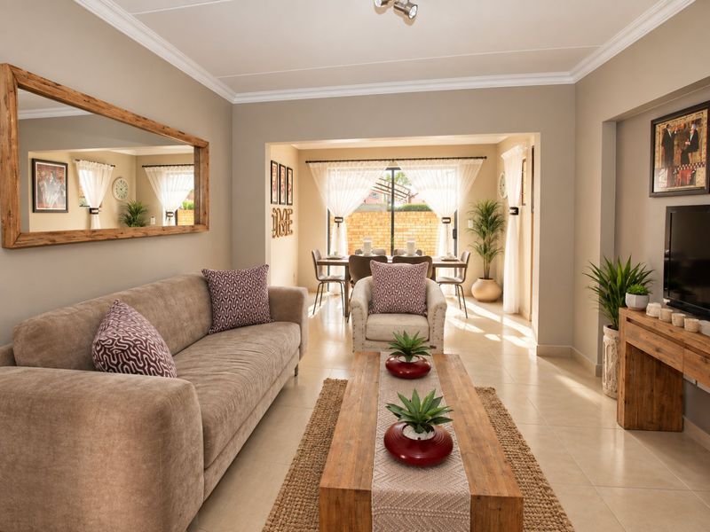 A bright open-plan living and dining area featuring neutral tiled flooring, cove cornicing, and a large sliding door providing access to the rear patio.