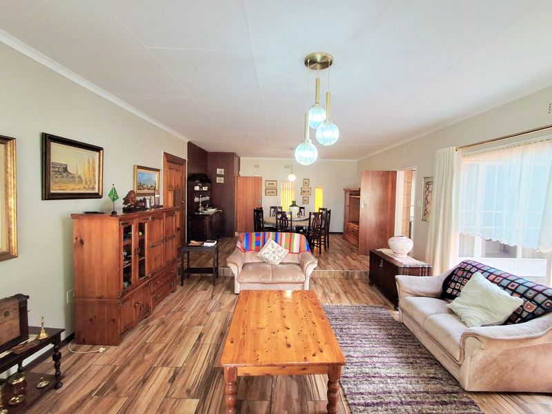 Spacious open-plan living and dining area featuring tiled flooring, a raised dining platform, and classic pendant lighting throughout the connected living spaces.