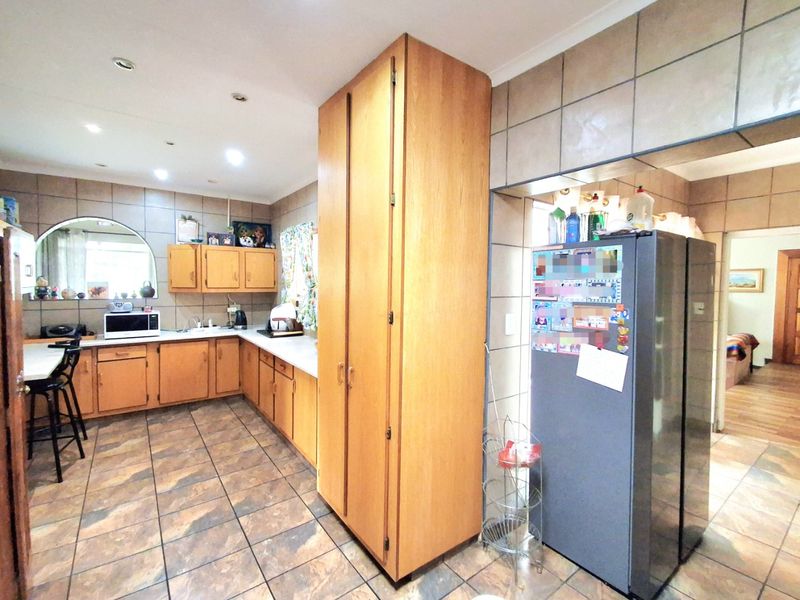A functional kitchen featuring extensive wooden cabinetry, tiled flooring, and a tiled backsplash, offering a classic layout with ample storage space.