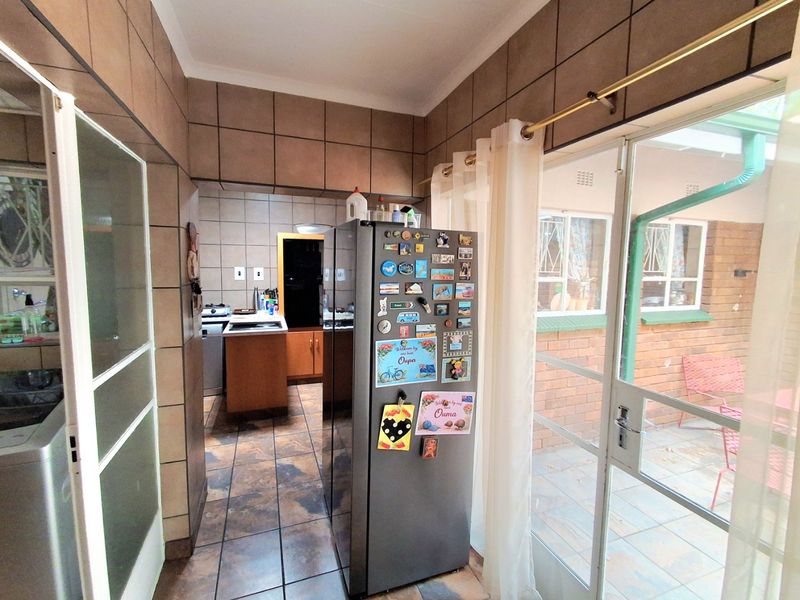 A functional scullery area featuring tiled walls and flooring, with direct access to an outdoor patio through a sliding glass door.