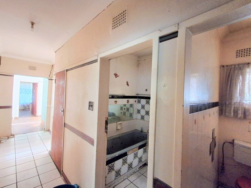 A dated bathroom featuring a built-in bathtub and original ceramic tiling, currently in need of significant renovation and cosmetic updates.