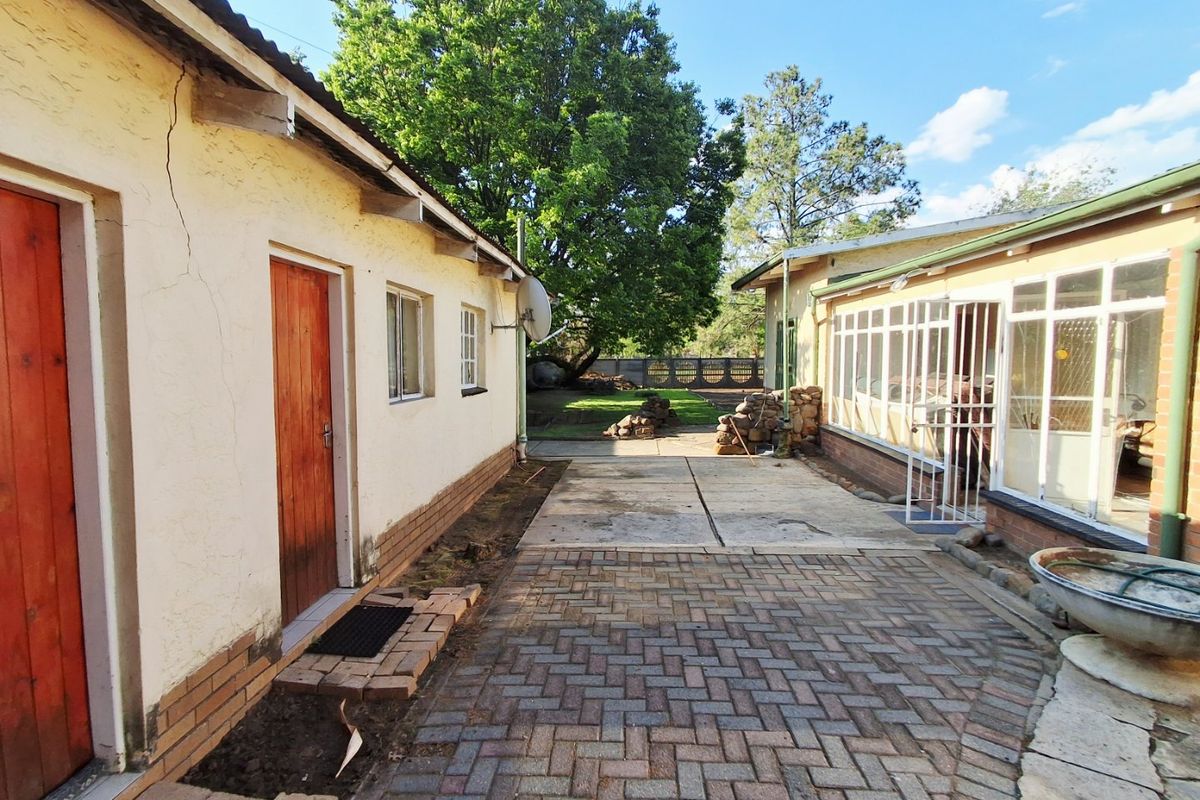 Rear exterior view showing a paved courtyard area between two building structures with an enclosed patio and garden access.