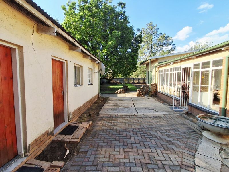 Rear exterior view showing a paved courtyard area between two building structures with an enclosed patio and garden access.