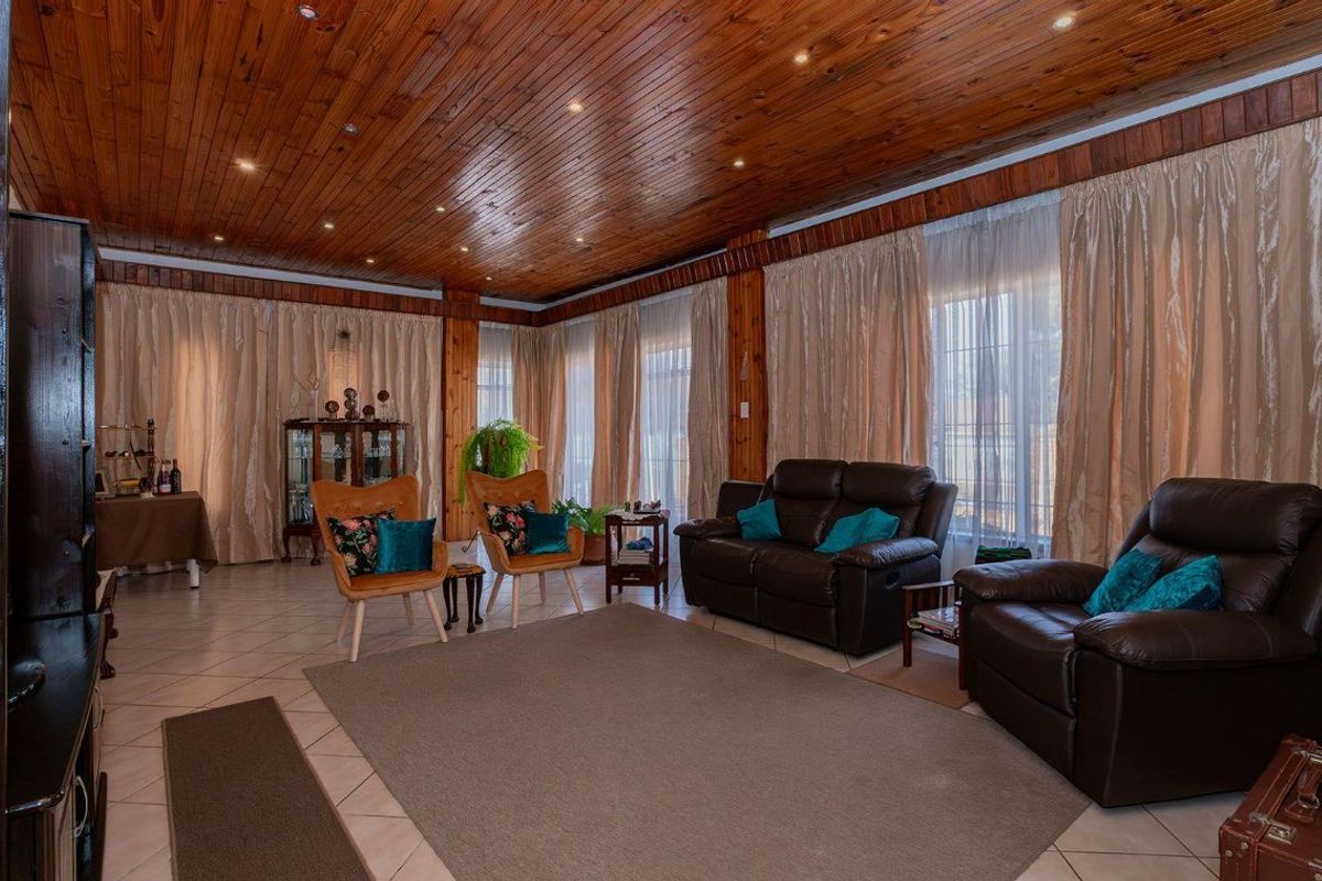 Spacious living room featuring a warm timber-clad ceiling with recessed lighting and large glass doors providing ample natural light.