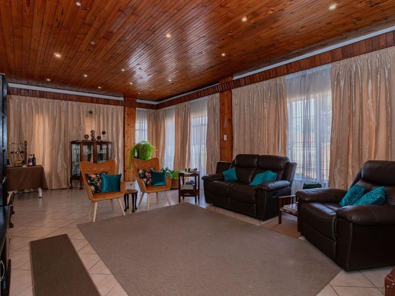 Spacious living room featuring a warm timber-clad ceiling with recessed lighting and large glass doors providing ample natural light.