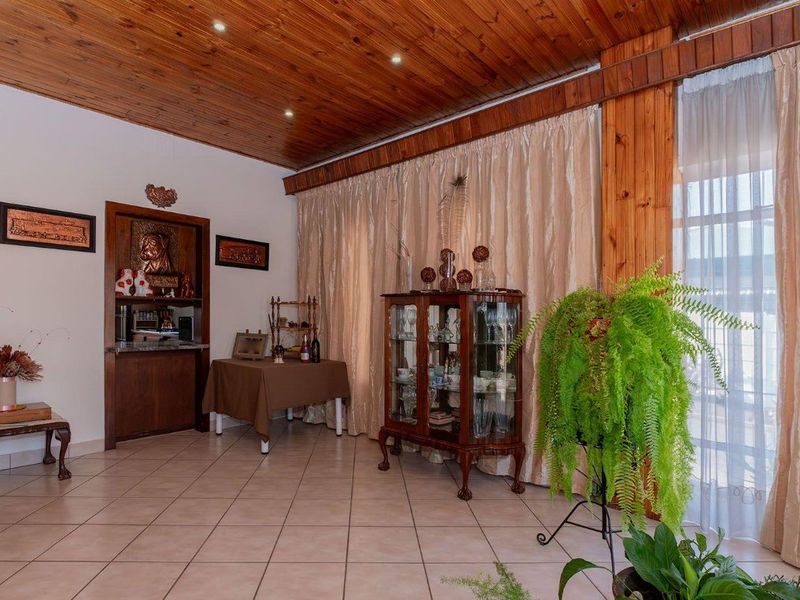 Spacious living area featuring a warm timber-clad ceiling, recessed lighting, tiled flooring, and a built-in bar nook with direct access to the outdoors.