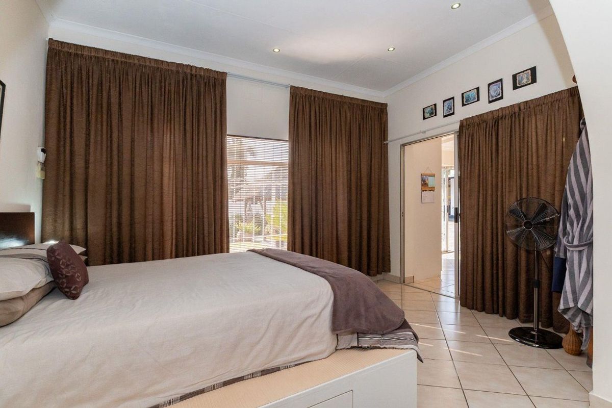 A bedroom featuring tiled flooring, recessed downlighting, and a sliding door providing access to an adjoining space.