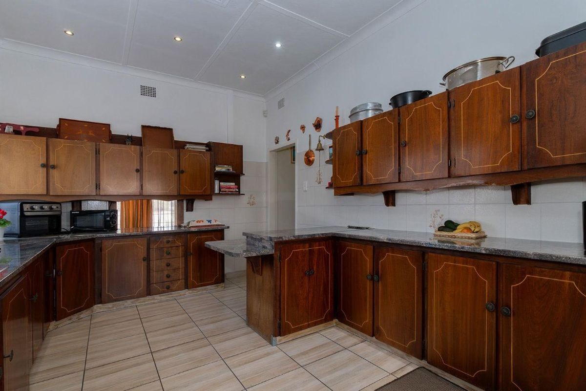 A functional kitchen featuring traditional wooden cabinetry, granite countertops, tiled flooring, and recessed ceiling lighting, offering a classic layout with ample storage space.