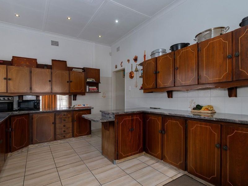 A functional kitchen featuring traditional wooden cabinetry, granite countertops, tiled flooring, and recessed ceiling lighting, offering a classic layout with ample storage space.