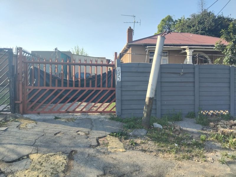 Front exterior view of the property featuring a metal gate, precast boundary wall, and tiled roof structure.