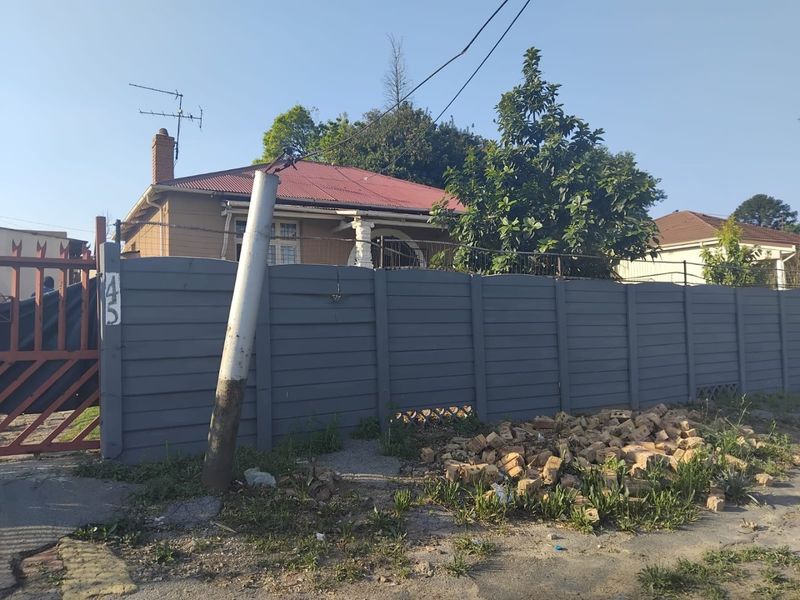 Front view of a residential property featuring a precast concrete boundary wall, metal gate, and a tiled roof structure.