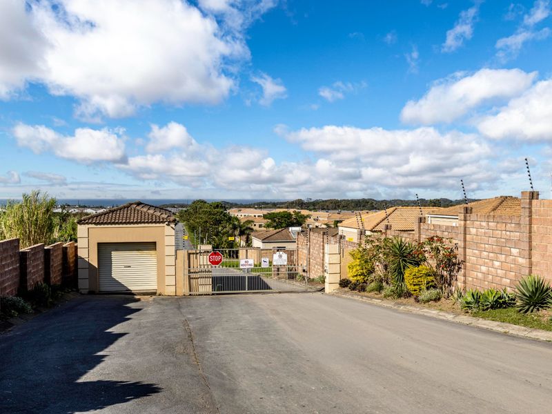 A view of the secure gated entrance to the residential estate, featuring brick boundary walls, electric fencing, and an automated security gate.