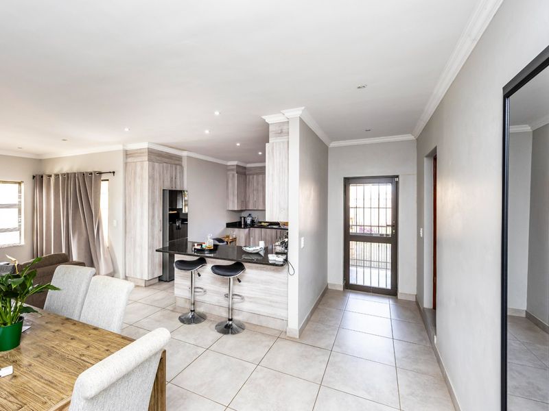 Open-plan living and kitchen area featuring tiled flooring, modern built-in cabinetry, granite countertops, and recessed lighting, creating a bright and functional space.