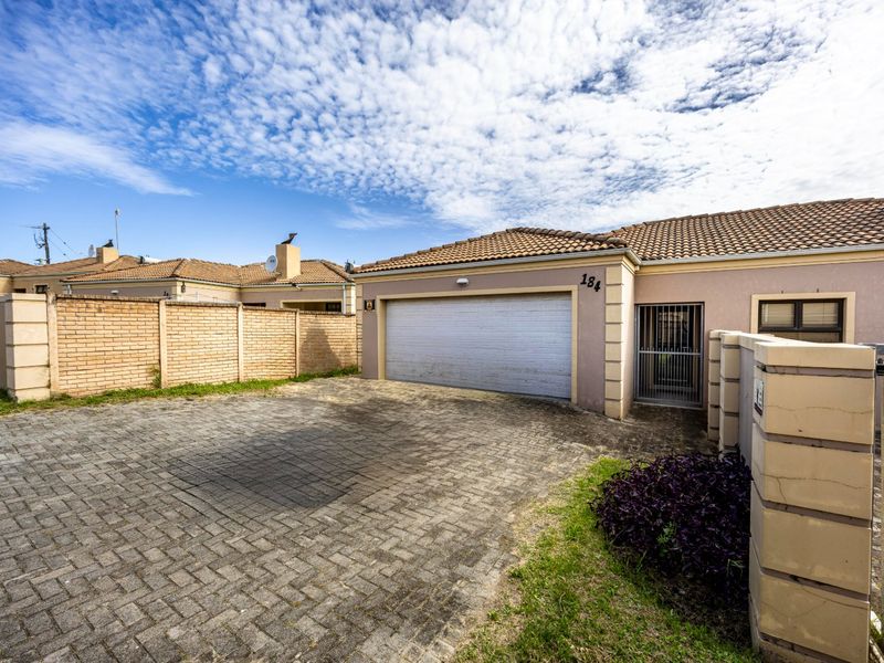 Front exterior view of the property featuring a paved driveway, single garage, and secure boundary walling.