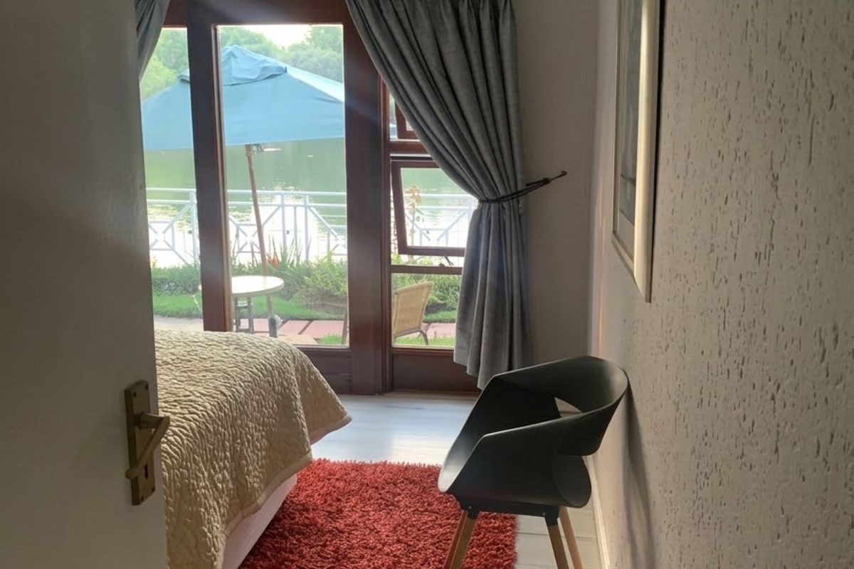 A bedroom featuring textured walls, laminate flooring, and a sliding glass door providing direct access to an outdoor patio area.