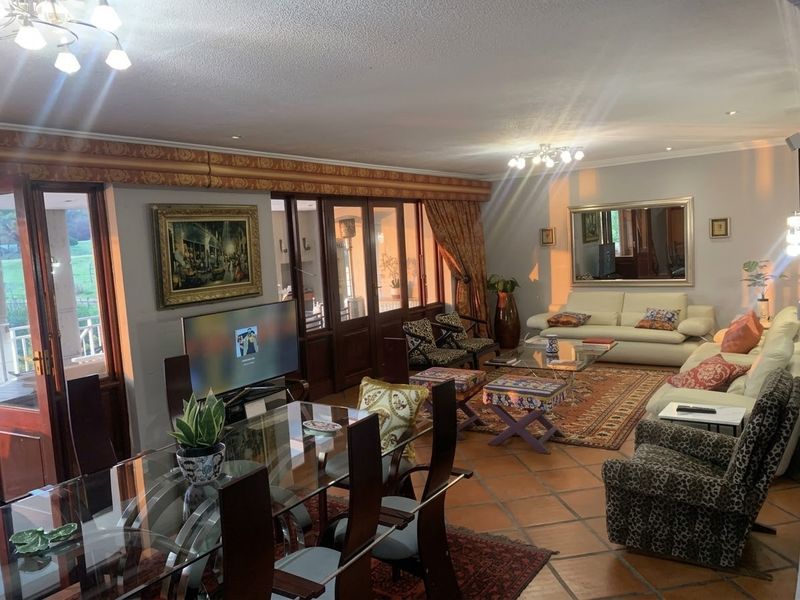 Spacious open-plan living and dining area featuring traditional terracotta floor tiles, timber-framed glass doors, and warm ambient lighting.