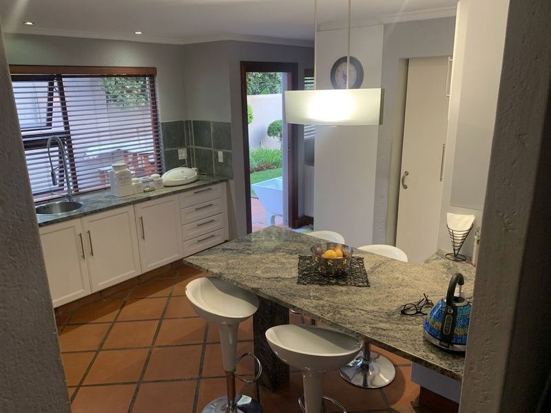 A functional kitchen featuring granite countertops, a central island with breakfast bar seating, tiled flooring, and direct access to the outdoor area.