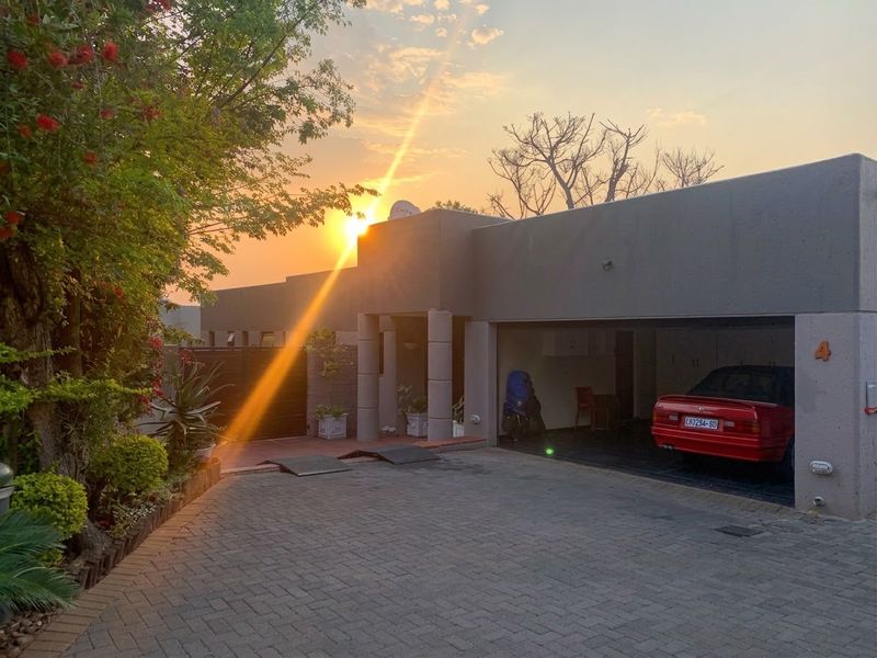 Front exterior view of the property featuring a paved driveway, double garage, and modern architectural facade at sunset.