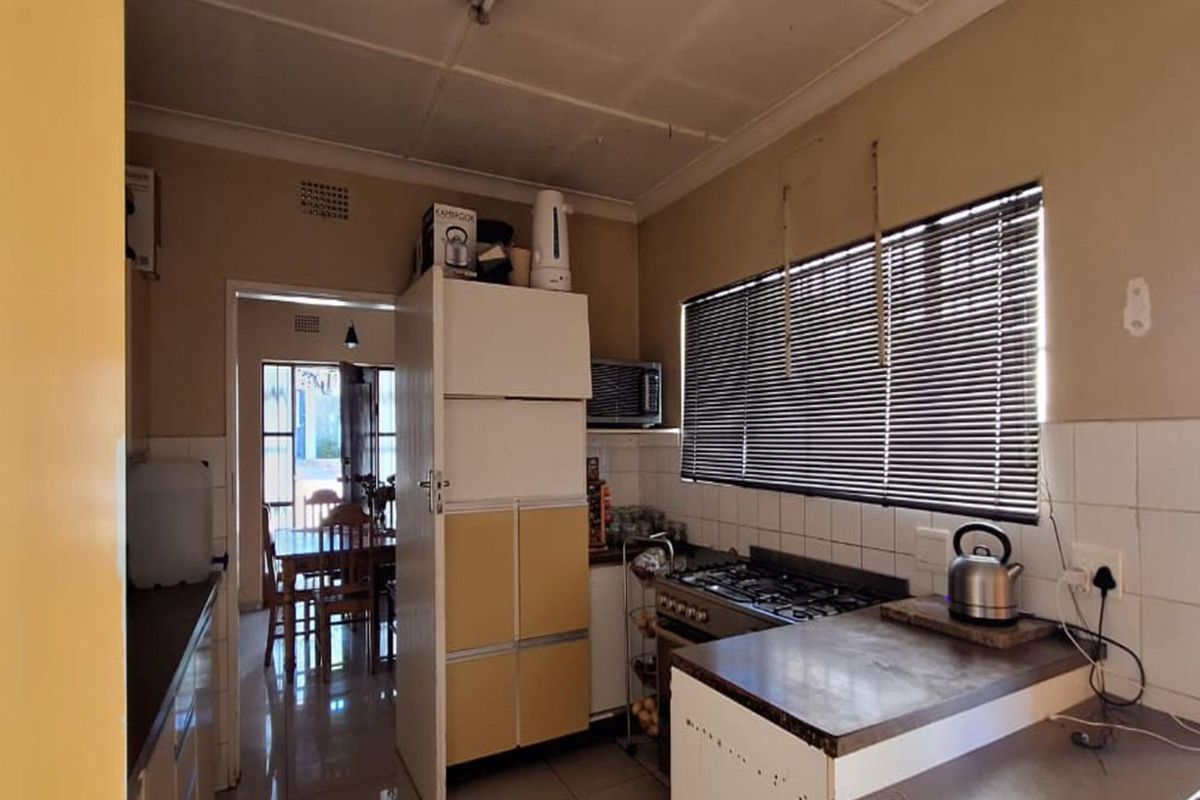 A functional kitchen featuring a gas hob, built-in oven, tiled splashbacks, and laminate countertops, offering potential for a modern renovation.