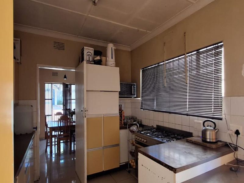 A functional kitchen featuring a gas hob, built-in oven, tiled splashbacks, and laminate countertops, offering potential for a modern renovation.