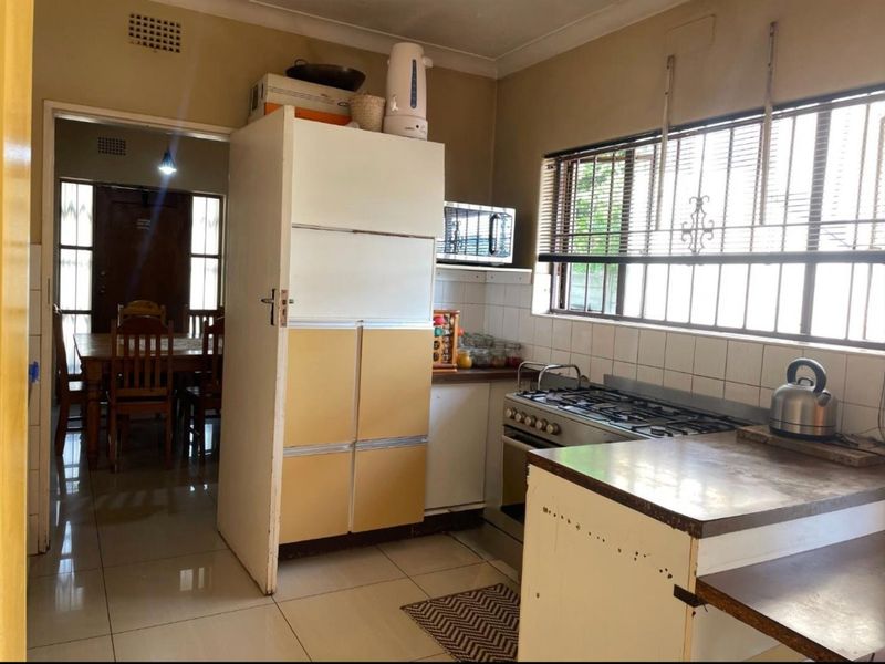A functional kitchen featuring tiled flooring, built-in cabinetry, and a gas stove, with direct access to the adjacent dining area.