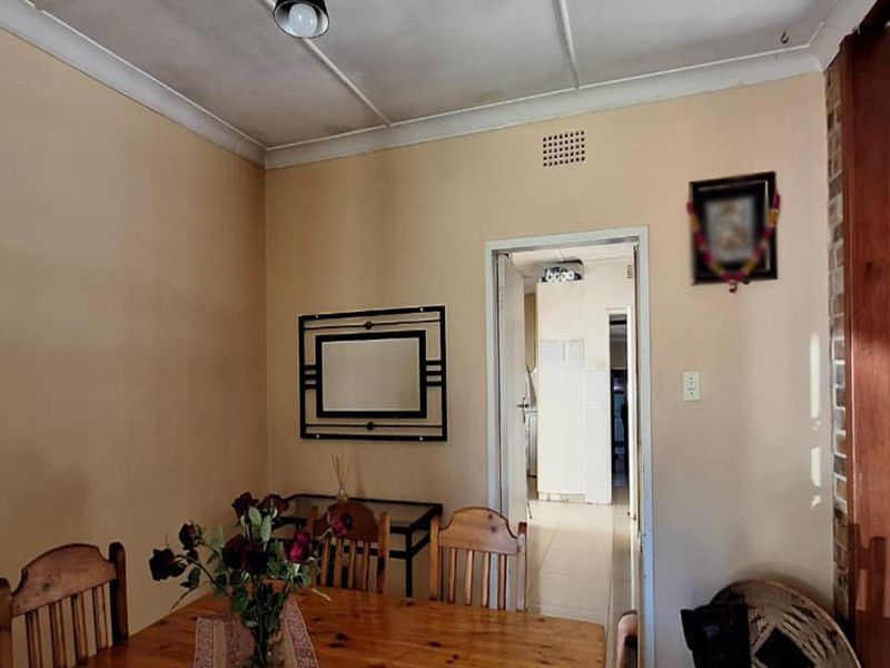 Dining area featuring neutral walls, cove cornicing, and an exposed brick feature wall, providing a functional space with access to adjacent rooms.
