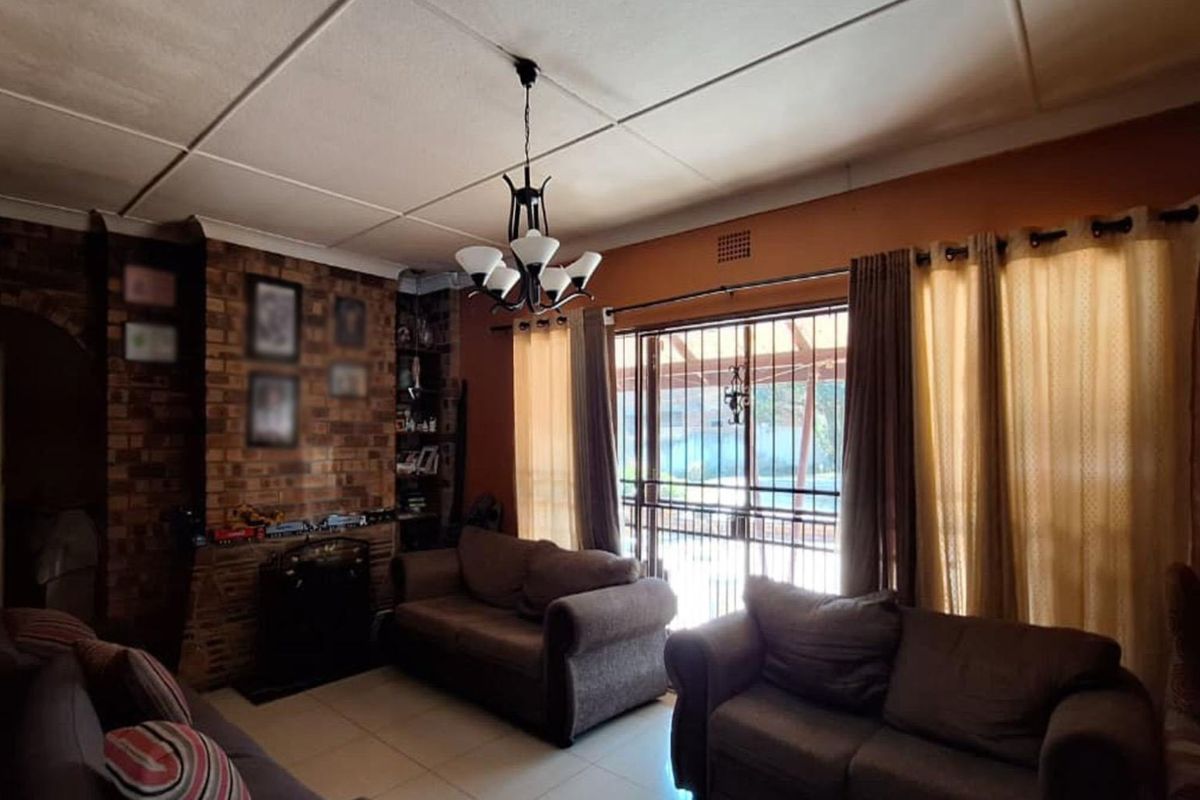 A living room featuring an exposed brick fireplace, tiled flooring, and sliding glass doors leading to an outdoor area.