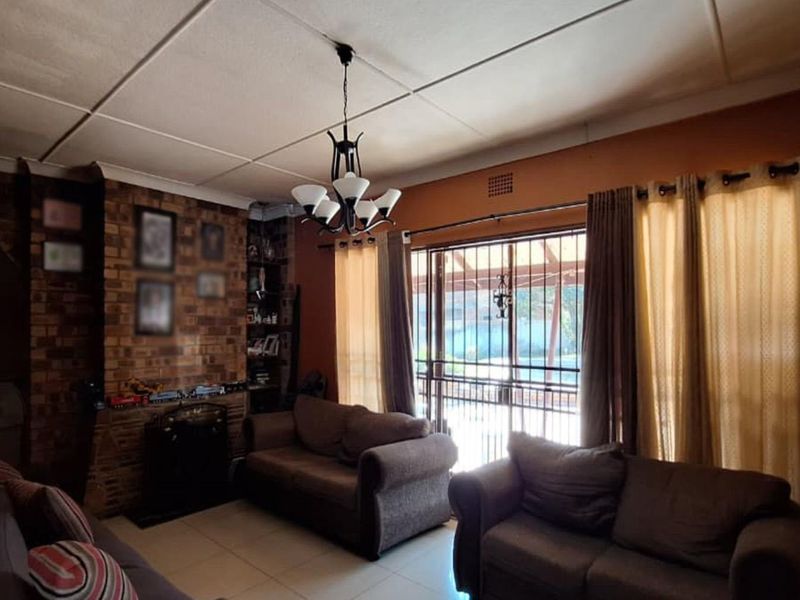 A living room featuring an exposed brick fireplace, tiled flooring, and sliding glass doors leading to an outdoor area.