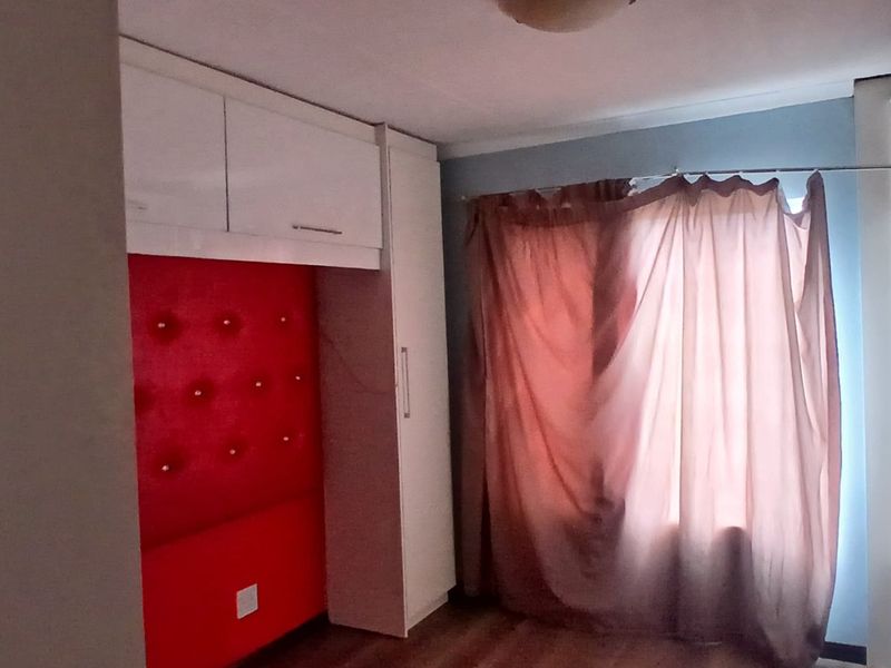 A bedroom featuring built-in cupboards and laminate flooring, offering a functional space with potential for modern updates.