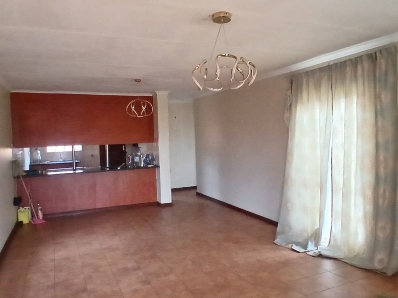 Spacious open-plan living and kitchen area featuring tiled flooring, built-in cabinetry, and sliding door access to the exterior.