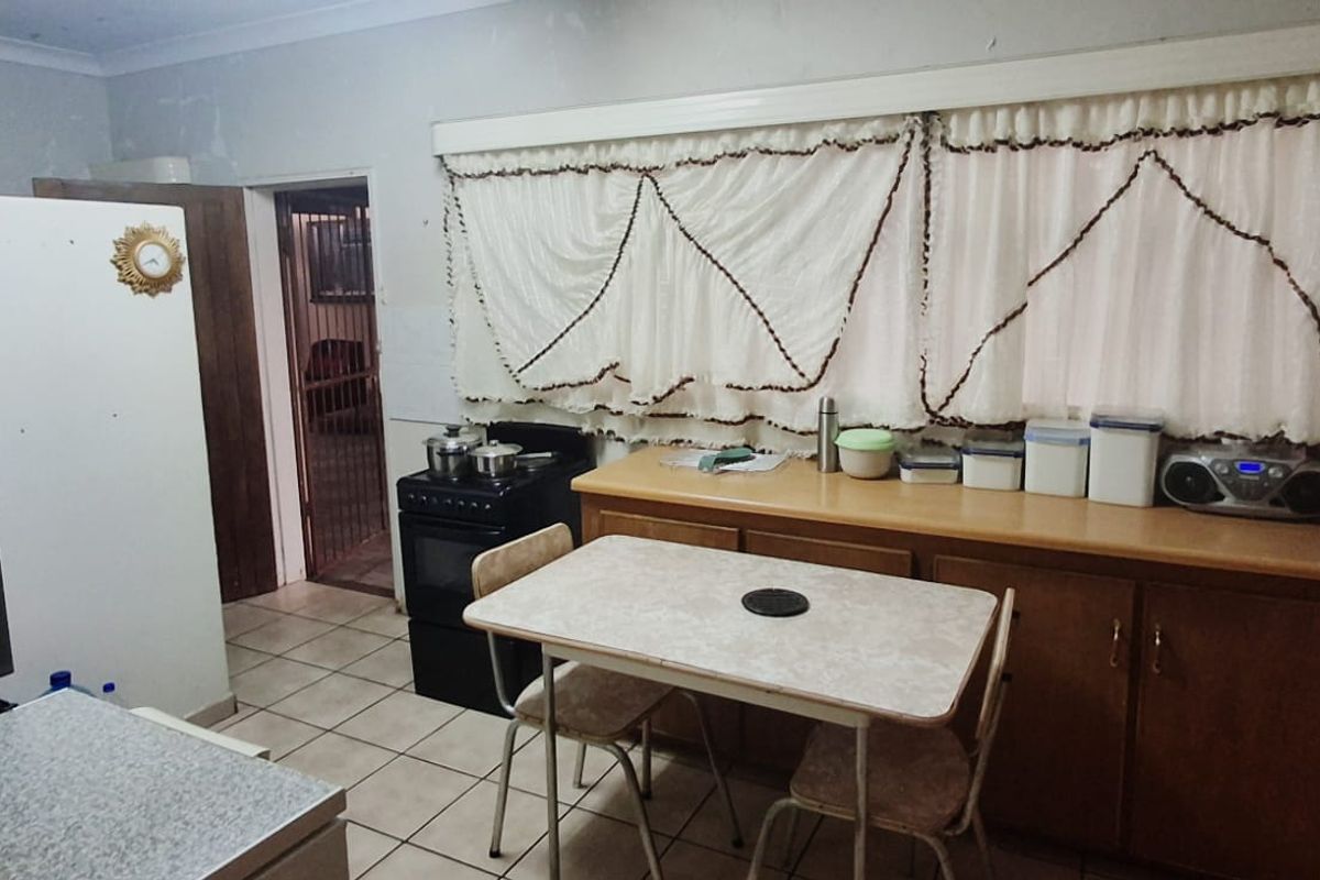 A dated kitchen featuring wood-tone cabinetry, laminate countertops, and tiled flooring, offering potential for a modern renovation.