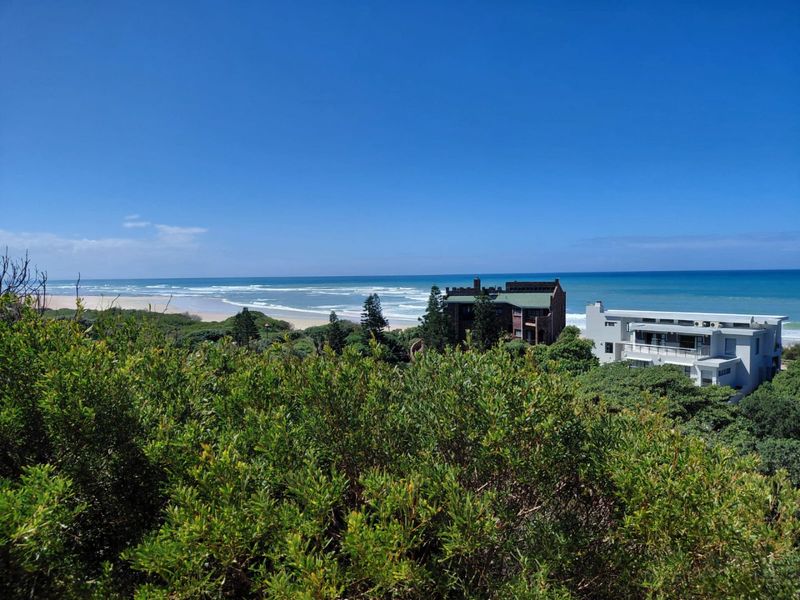 A scenic elevated view overlooking the coastline, ocean, and surrounding natural vegetation, highlighting the prime location of the property.