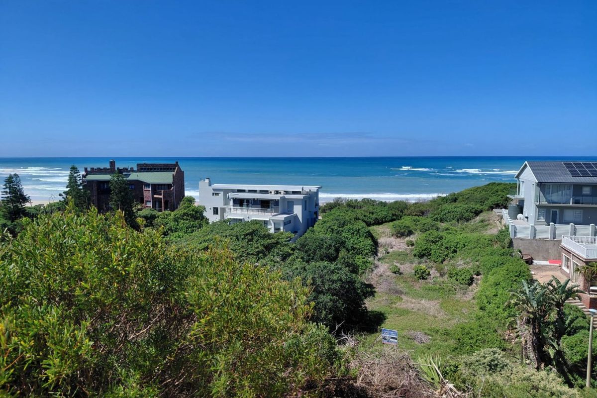 A scenic elevated view overlooking the coastal landscape, lush vegetation, and the ocean, showcasing the prime location of the vacant residential land.