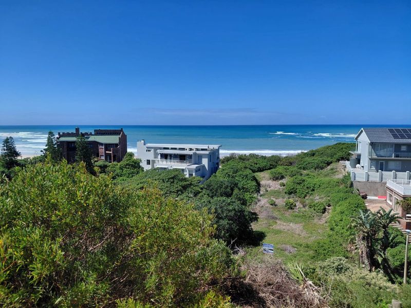 A scenic elevated view overlooking the coastal landscape, lush vegetation, and the ocean, showcasing the prime location of the vacant residential land.