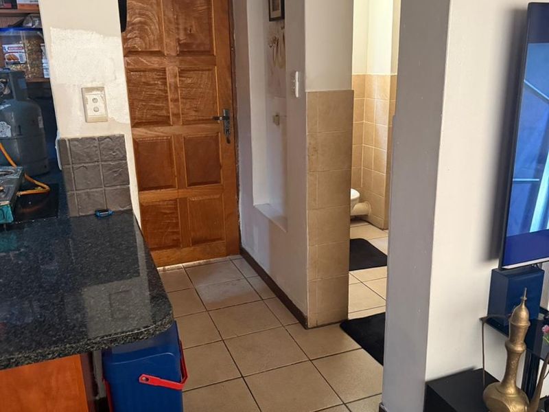 Open plan living area featuring tiled flooring, granite kitchen countertops, and direct access to a bathroom and exterior door.