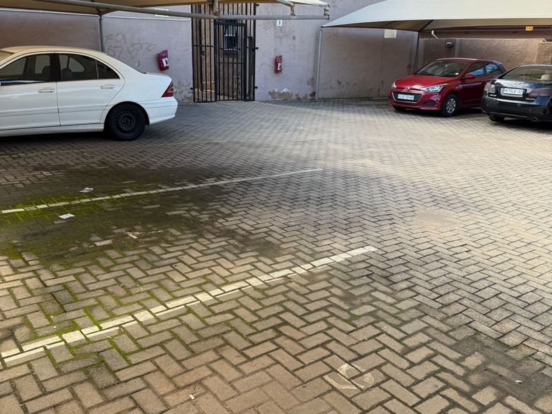 Outdoor parking area featuring paved surfaces, shade cloth carports, and secure gated access.