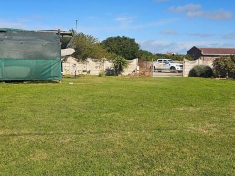 A spacious residential plot featuring a well-maintained lawn, enclosed by a precast concrete boundary wall and a metal access gate.