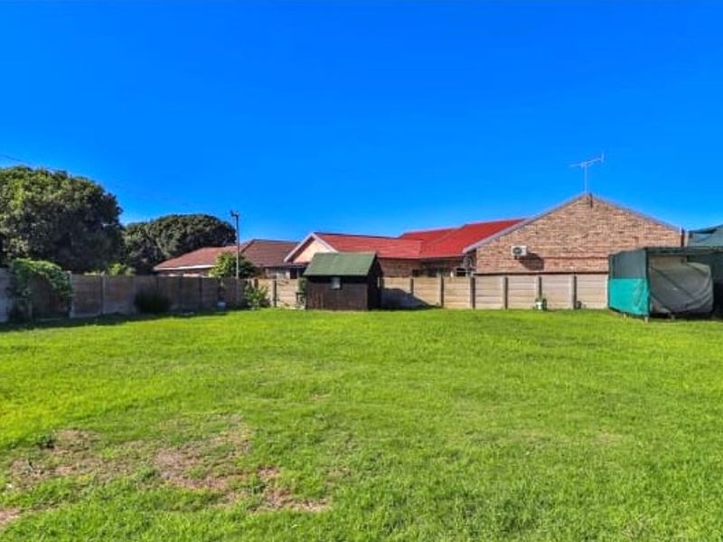 A spacious, level residential plot featuring a well-maintained lawn, enclosed by precast concrete boundary walls, including a small storage shed.