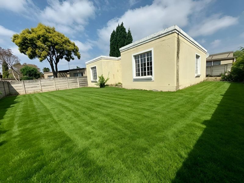 A spacious rear garden featuring a well-maintained lawn and a precast concrete boundary wall, providing a private outdoor space.