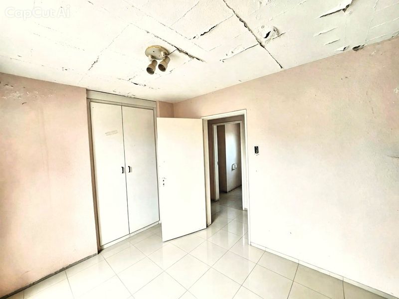 An empty bedroom featuring tiled flooring and a built-in wardrobe, currently requiring significant ceiling repairs and cosmetic updates.