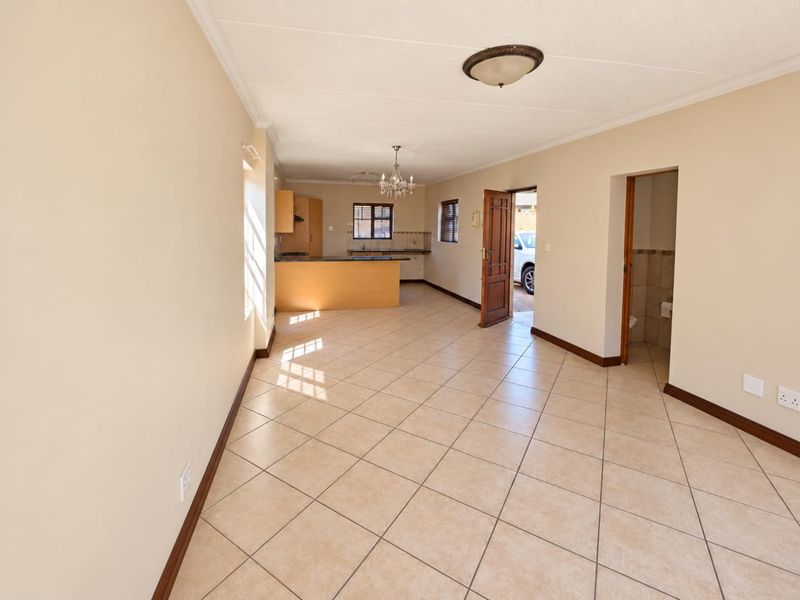 Spacious open-plan living and kitchen area featuring neutral wall tones, ceramic tiled flooring, and direct access to the exterior.