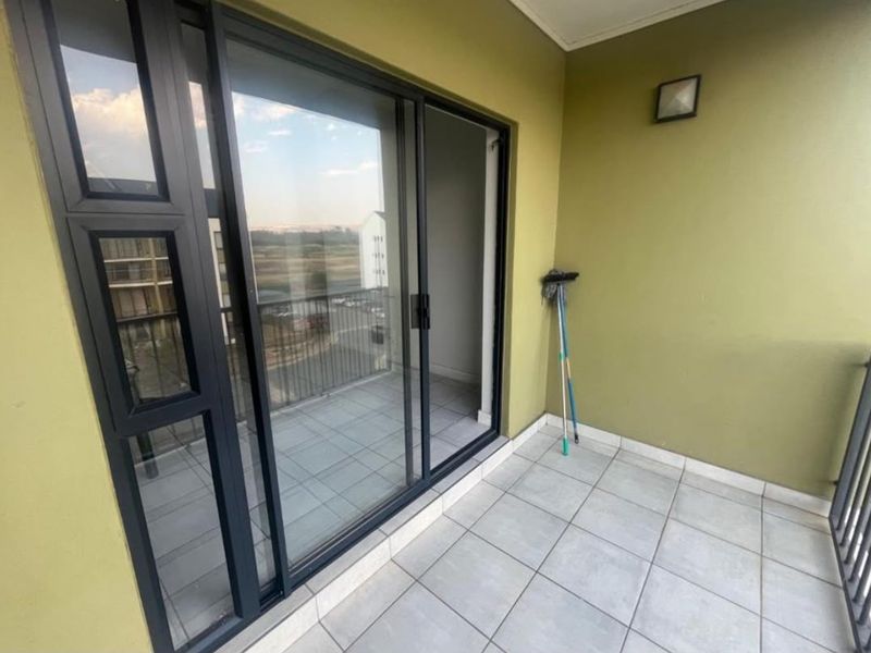A clean, tiled balcony featuring a modern sliding glass door and metal balustrade, offering a functional outdoor space.